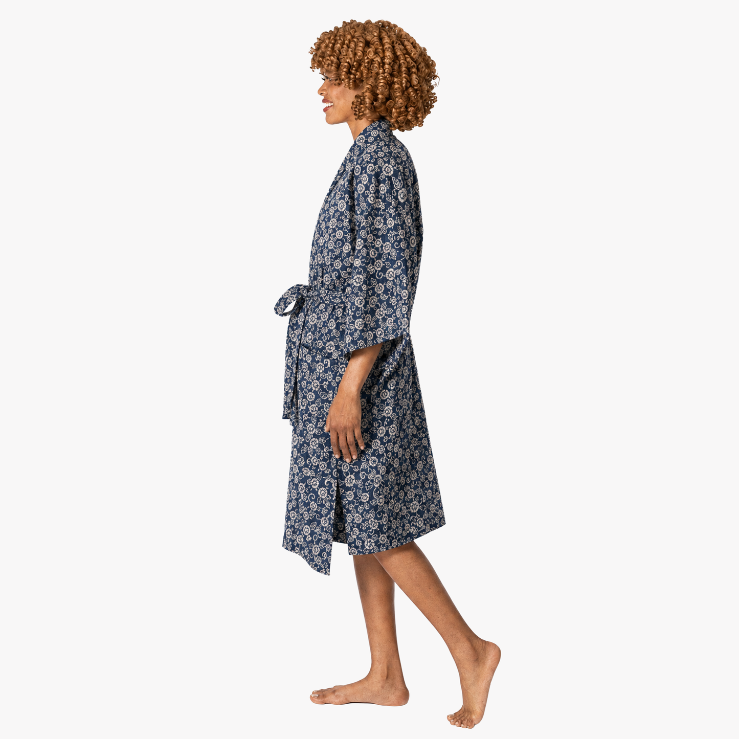 A woman wearing a navy blue and white floral print kimono-style robe, shown in profile against a plain light gray background.