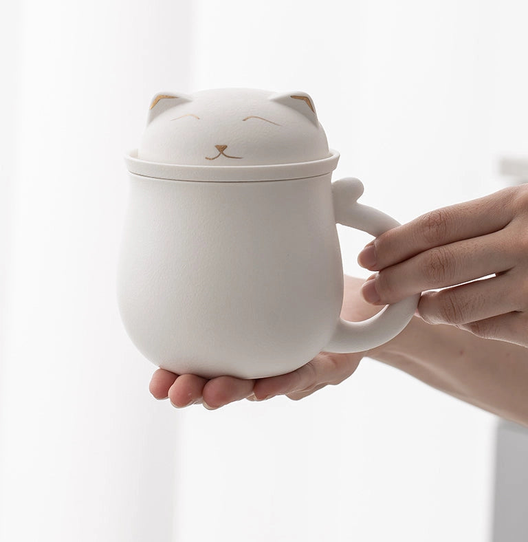 White cat-shaped mug with a lid held by a hand on a light background