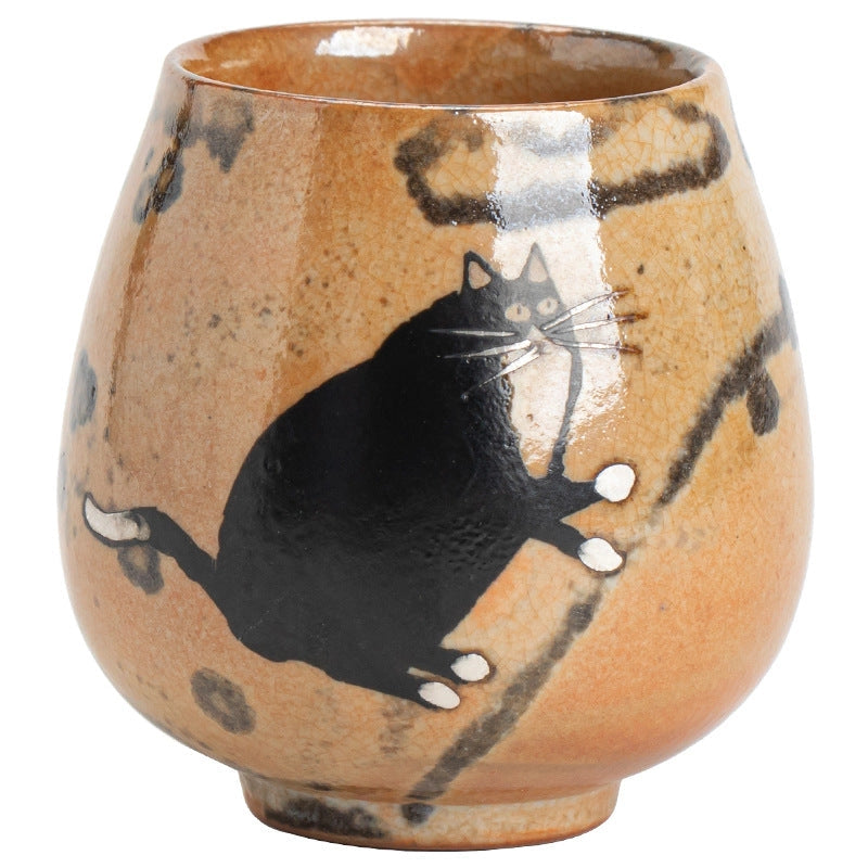 Brown teacup with a black painted cat on it.