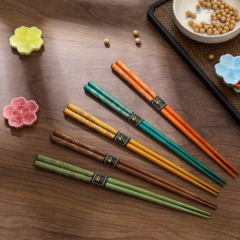 Set of five colorful Japanese reusable chopsticks on a wood table with other decor.