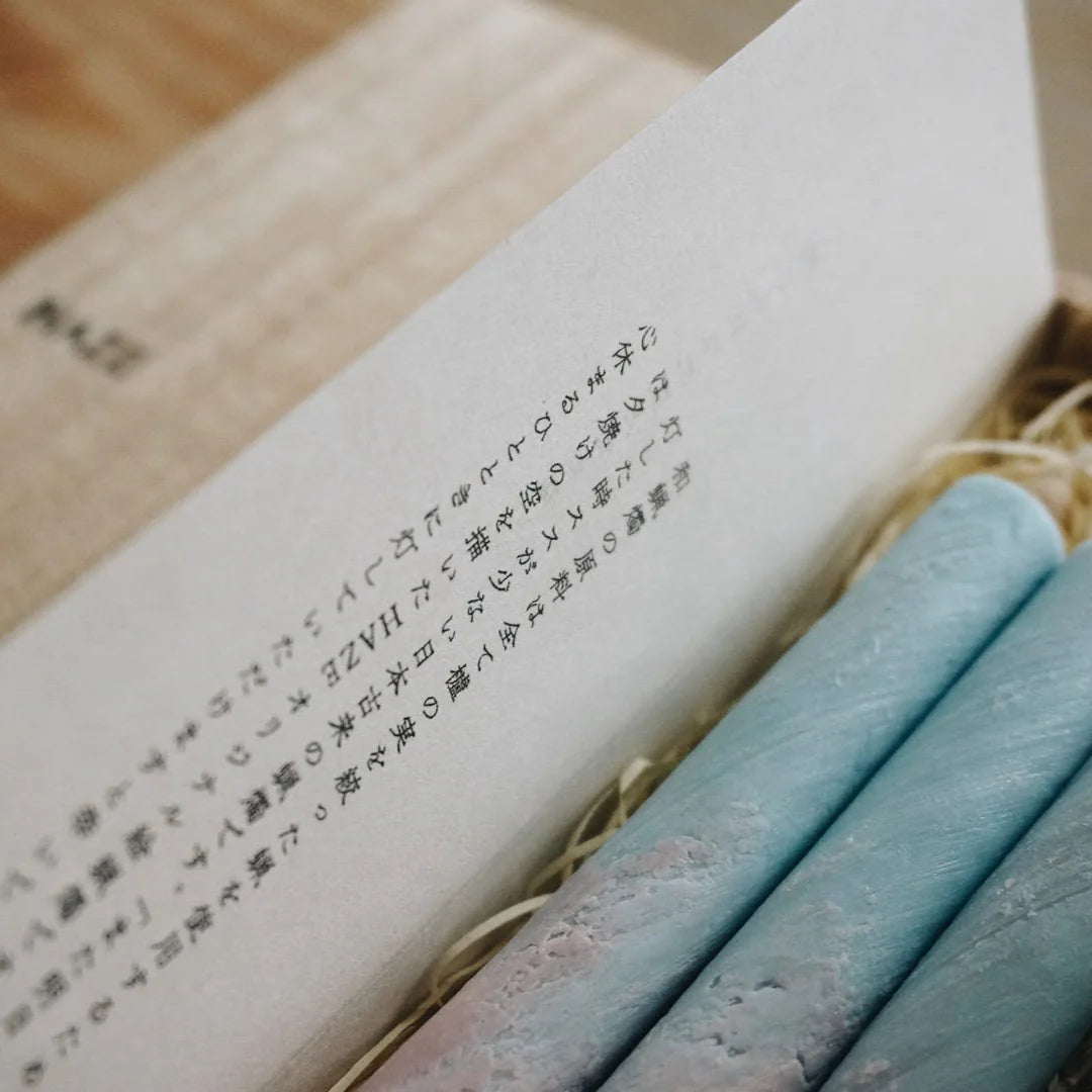 Rolled-up papers with text and a blue cylindrical candle on a wooden surface