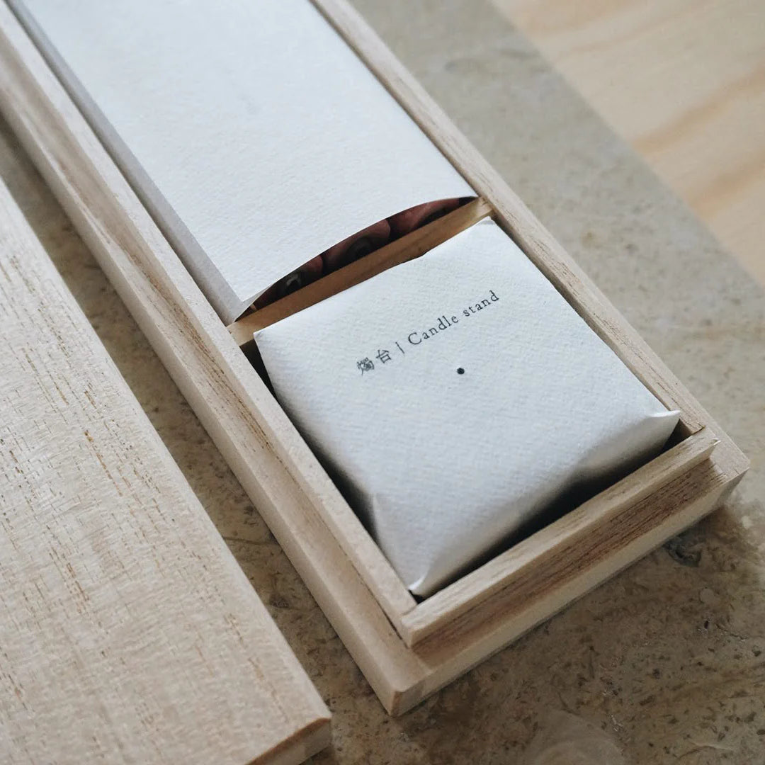 White candle holder with 'Candle stand' text in a wooden box on a wooden surface