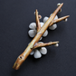 A decorative branch-shaped incense holder with white flower petals and small buds, photographed on a dark textured background.
