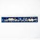 A long, narrow rectangular ceramic incense holder with a glossy deep blue background, decorated with white cherry blossom flowers and brown branches, on a plain white background.