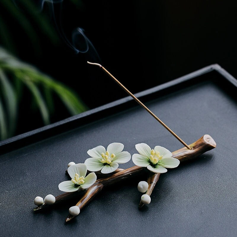Incense stick with floral decorations on a dark surface