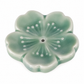 A glossy, five-petal flower-shaped ceramic incense holder in a light green glaze with white dotted details radiating from the center hole, shown on a plain white background.