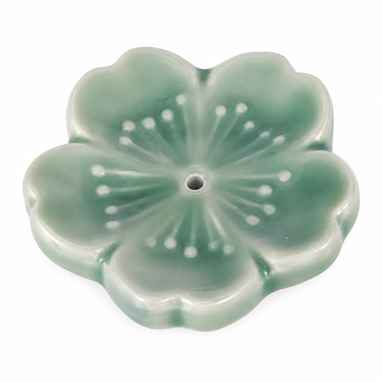 A glossy, five-petal flower-shaped ceramic incense holder in a light green glaze with white dotted details radiating from the center hole, shown on a plain white background.