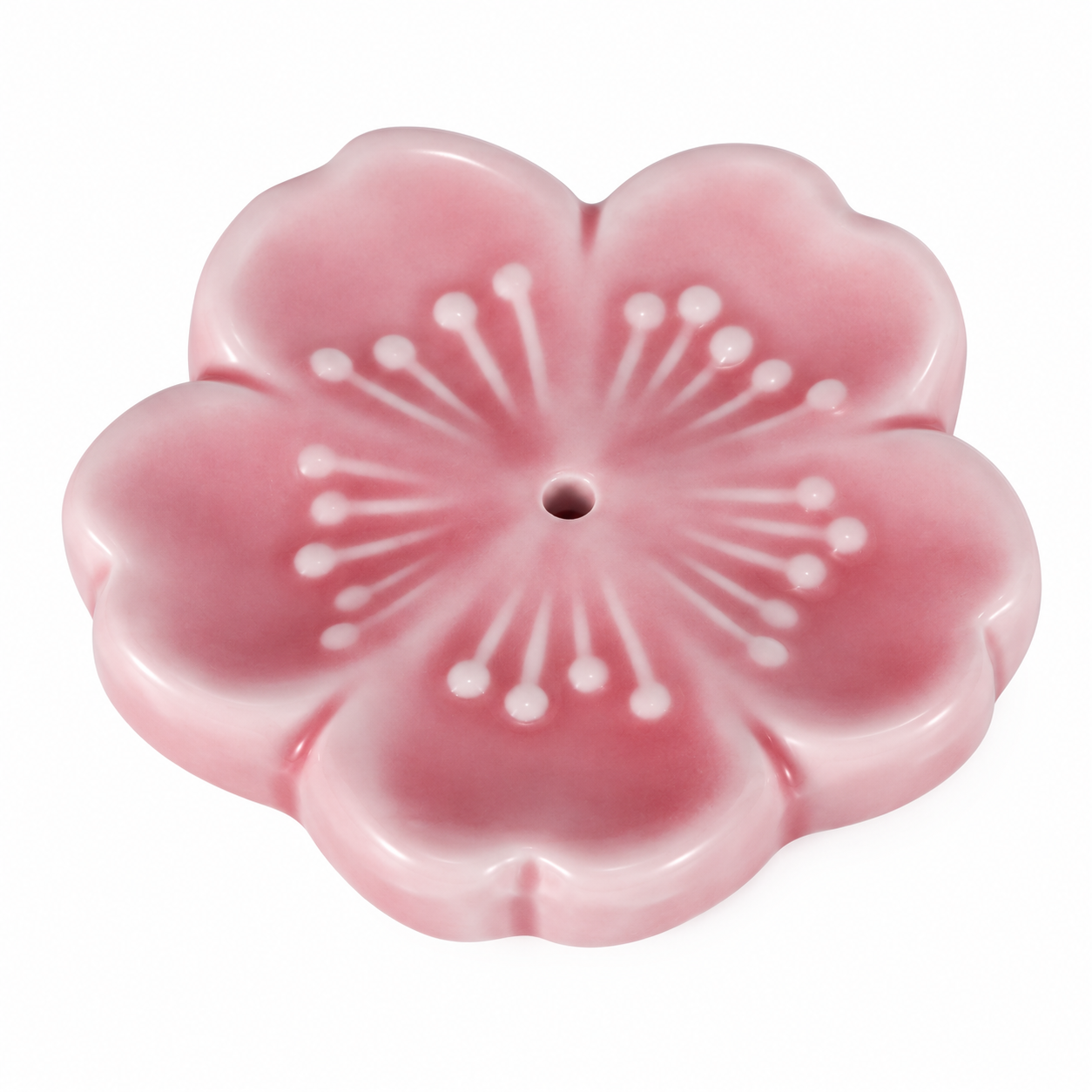 A pink cherry blossom-shaped ceramic incense holder with a central hole, featuring a glossy finish and white embossed petal details, set against a plain white background.