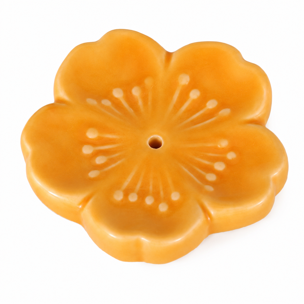 A glossy, five-petal flower-shaped ceramic incense holder in a warm orange-yellow glaze, featuring a central hole and subtle white floral details, set against a plain white background.