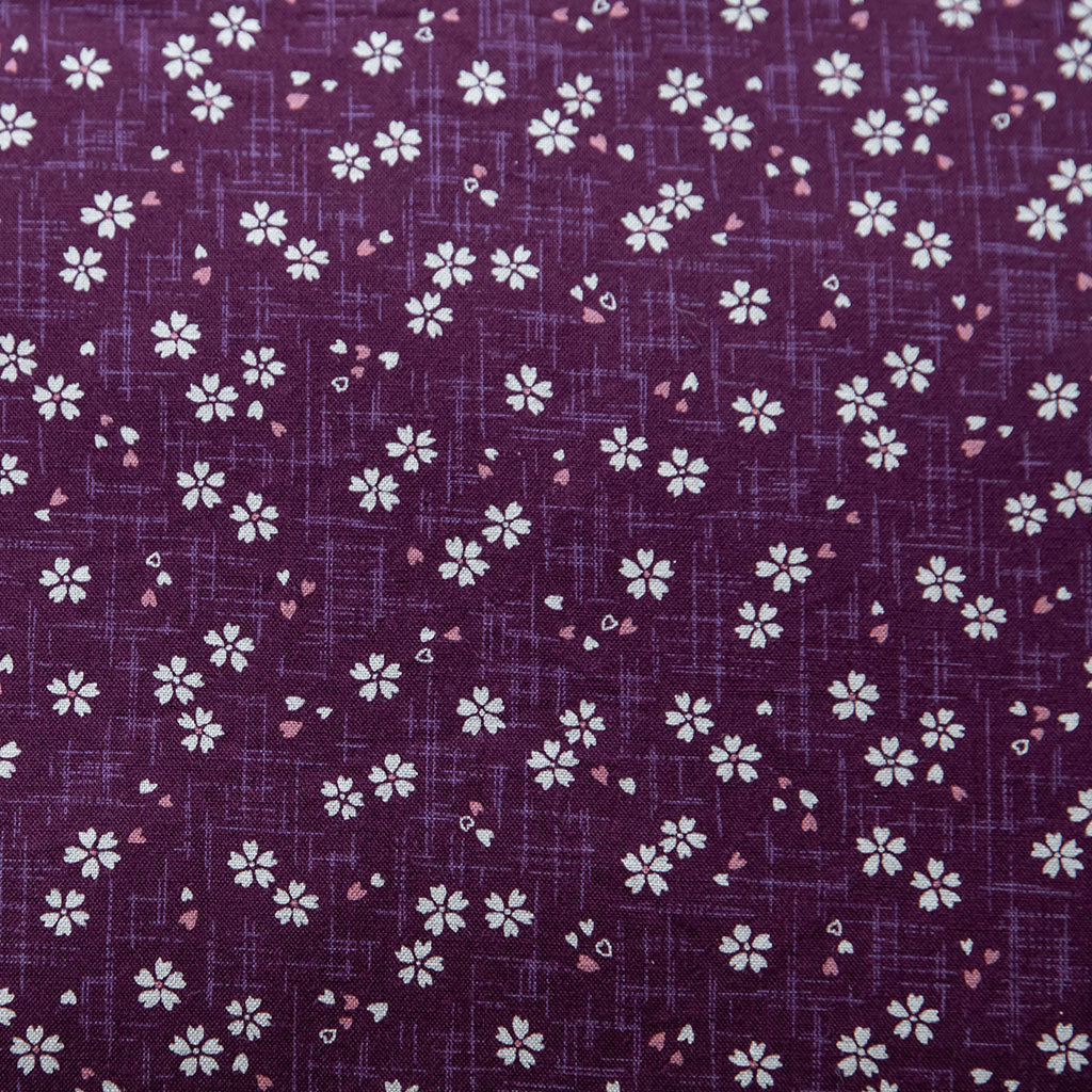 Close-up view of purple fabric with a Sakura pattern featuring white and pink flowers.