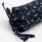 Roll of navy fabric with dragonfly pattern on a white background