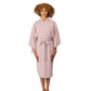 A woman wearing a dusty pink cotton robe with a tie belt, standing against a plain white studio background.