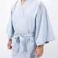 A person wearing a light blue kimono-style robe with wide sleeves and a self-tie belt, shown from the neck down against a plain white studio background.