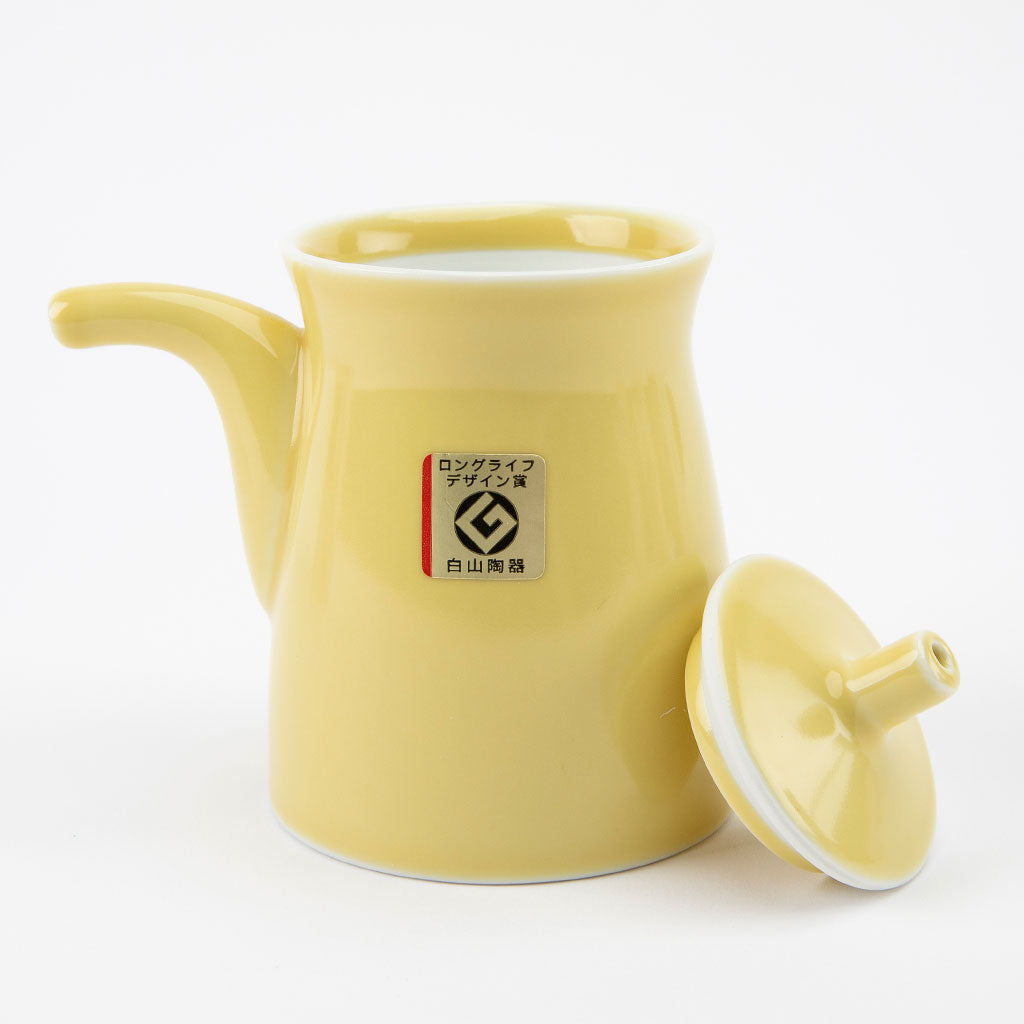 Yellow ceramic soy sauce dispenser with a lid on a white background