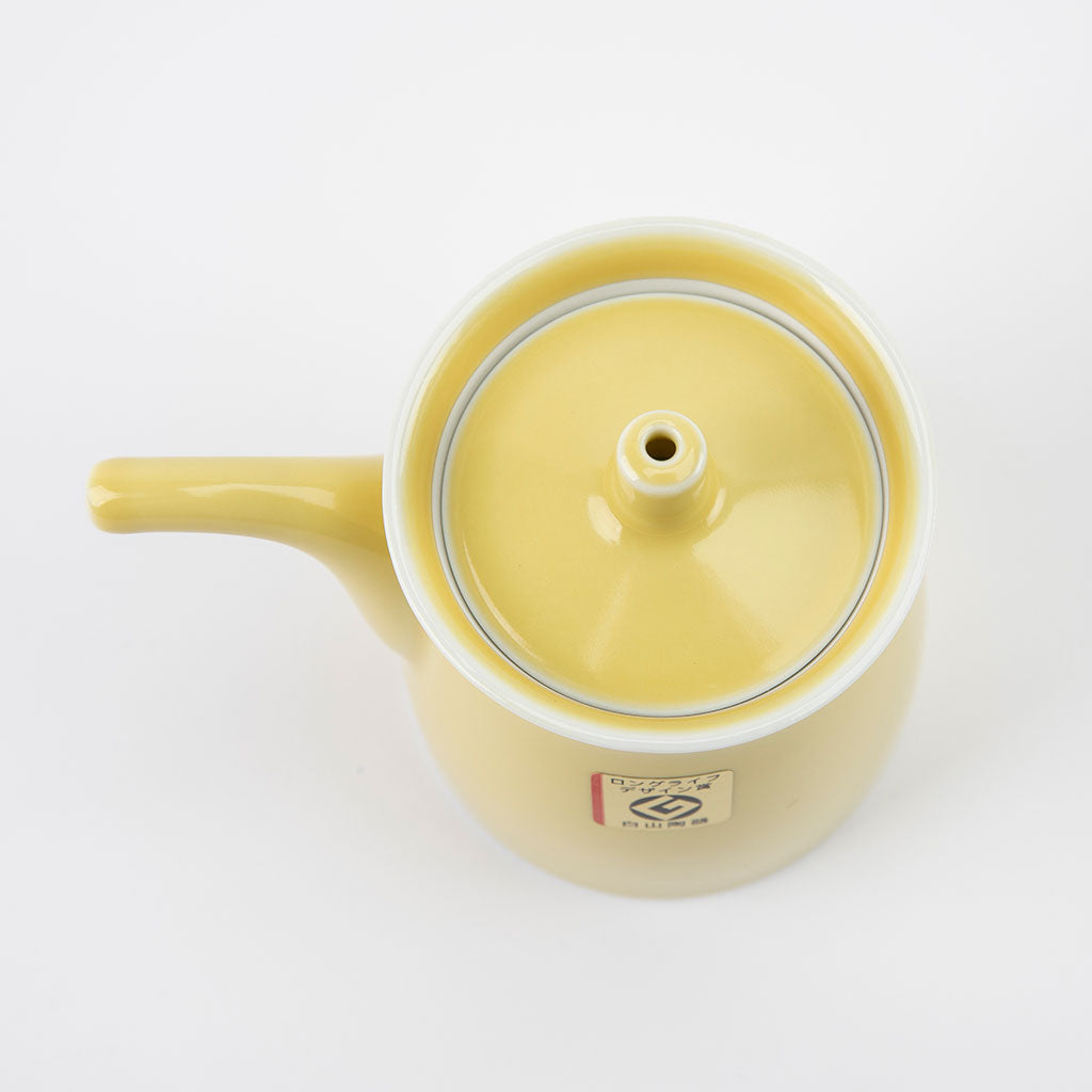 Yellow ceramic soy sauce dispenser with lid on a white background