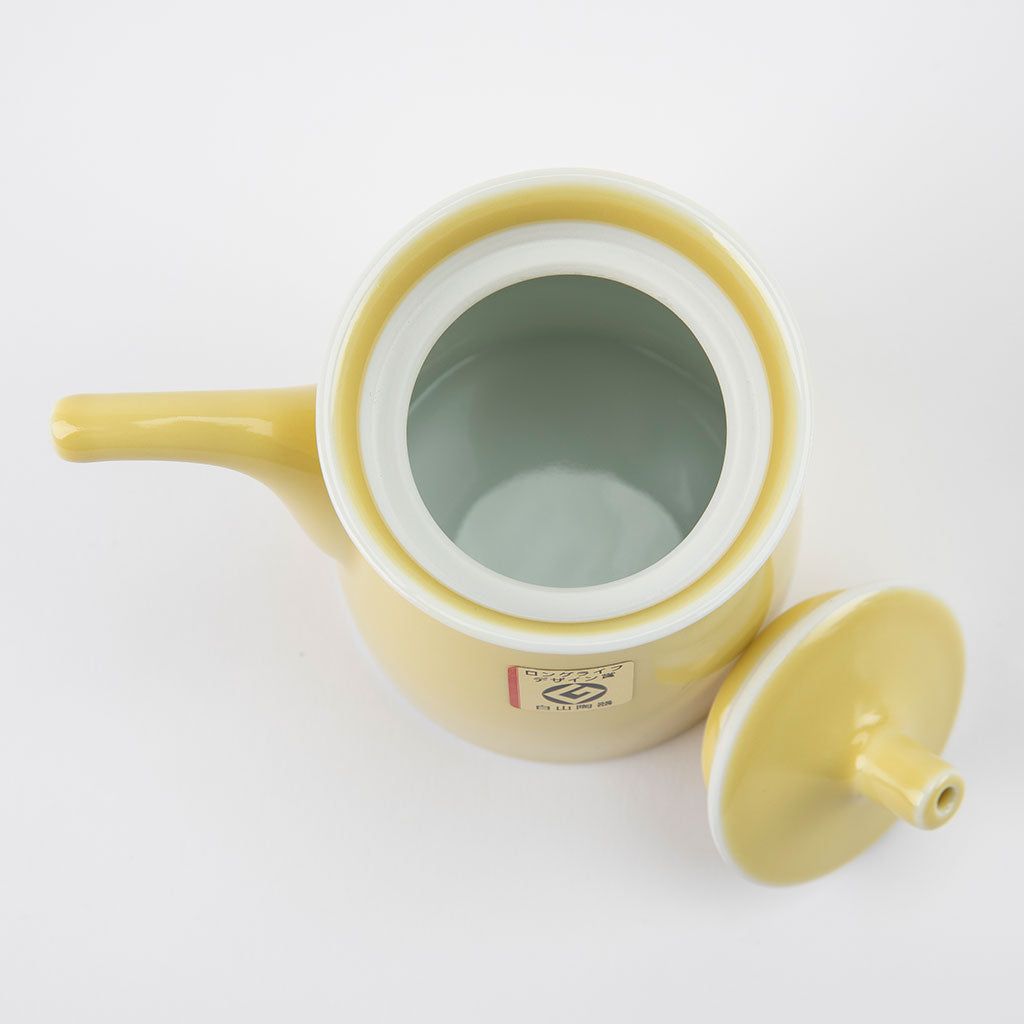 Yellow ceramic soy sauce dispenser with a white interior on a light gray background