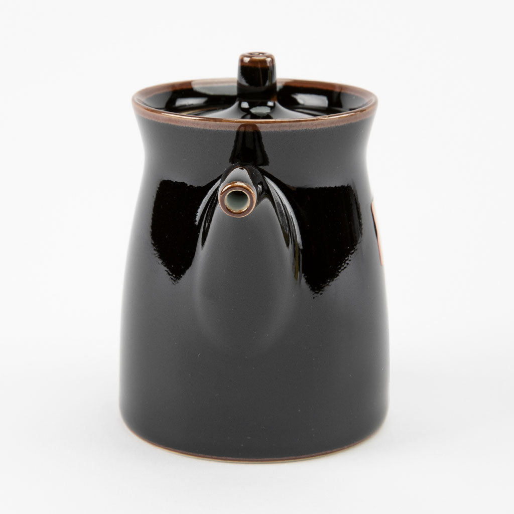 Black ceramic soy sauce dispenser with brown accents on a white background