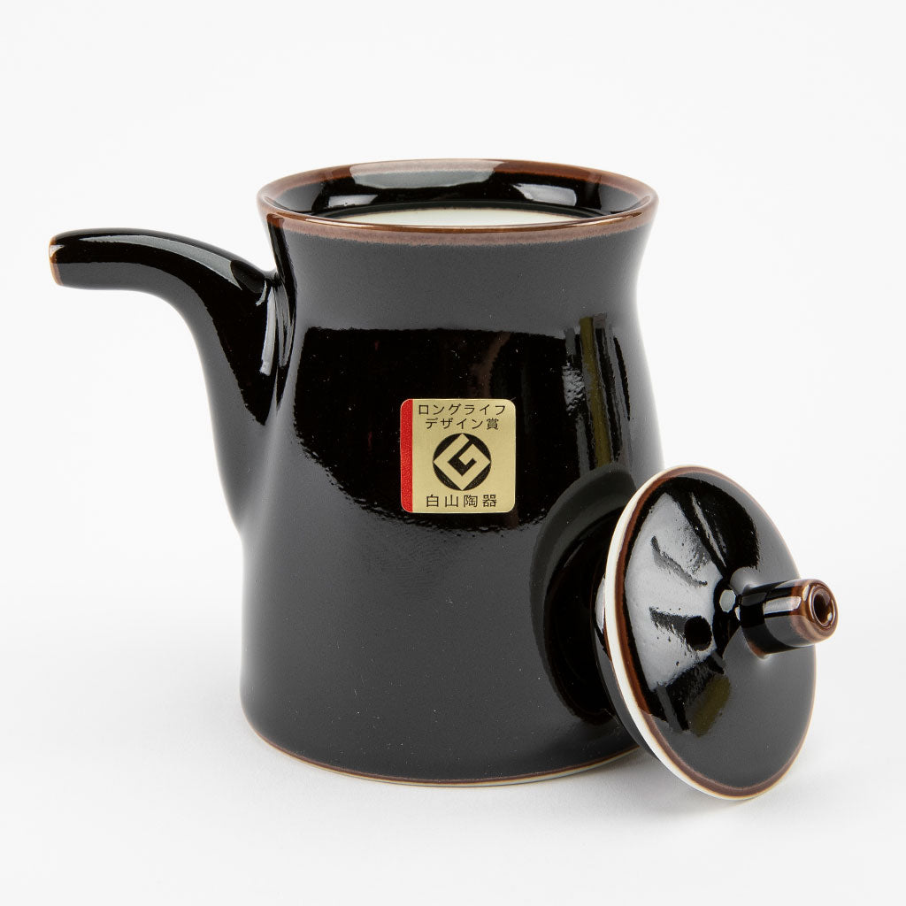 Black ceramic soy sauce dispenser with lid on a white background