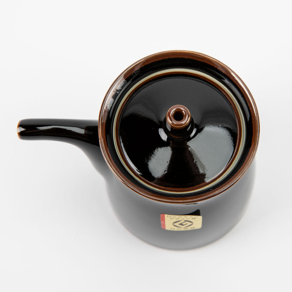 Black ceramic soy sauce dispenser with a lid on a white background