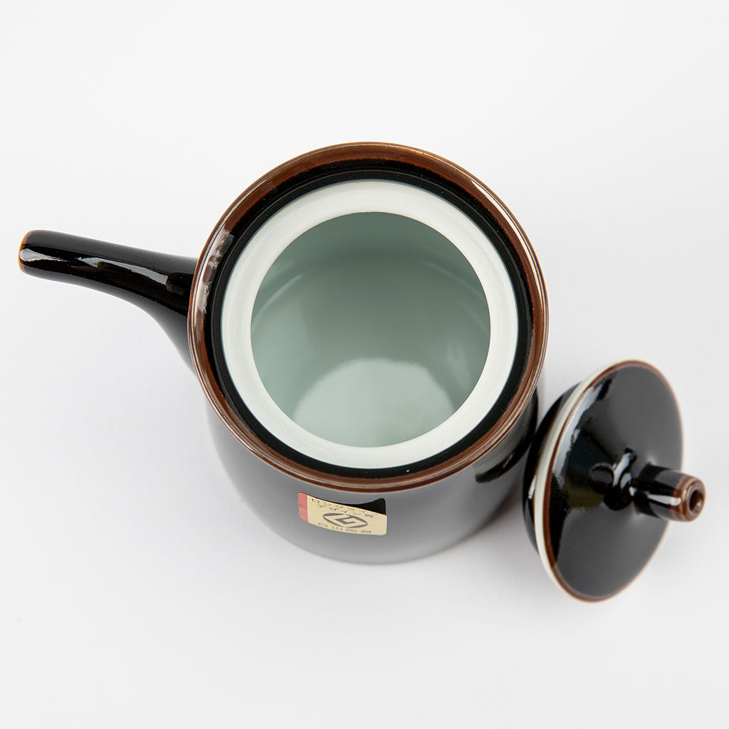 Black ceramic soy sauce dispenser with a lid on a white background