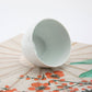 White ceramic bowl on a decorative fan with floral patterns