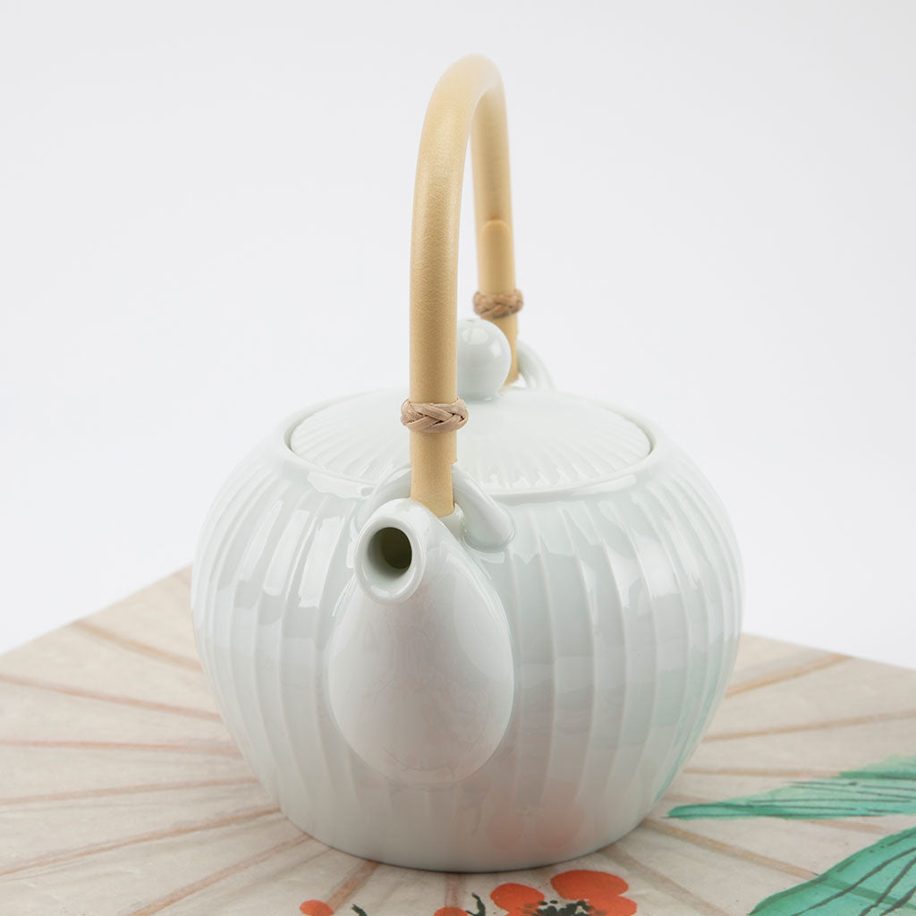 White ceramic teapot with a bamboo handle on a white background
