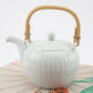 White teapot with a bamboo handle on a light background