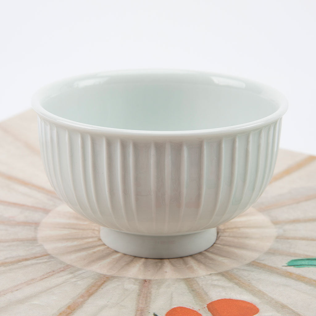 White ceramic bowl with ribbed texture on a patterned surface
