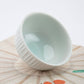 White ceramic bowl on a textured surface with a white background