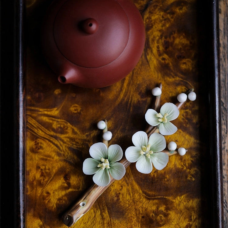 Red teapot on a dark wooden surface with decorative flowers