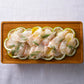 Raw fish fillets with lemon slices and herbs on a wooden platter.