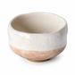 A handmade ceramic tea bowl with a glossy off-white glazed finish on the upper half and a textured, matte light brown unglazed band on the lower half, set against a plain white background.