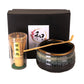 Matcha set including black box, bamboo whisk, spoon and black bowl on a white background.
