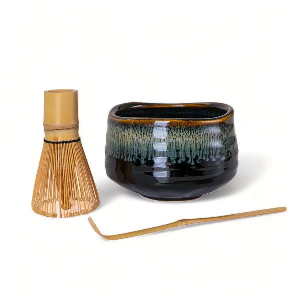 Ceramic matcha bowl with bamboo whisk and spoon on a white background
