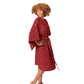 A woman modeling a short red robe with a small white floral pattern, standing barefoot against a plain white studio background.