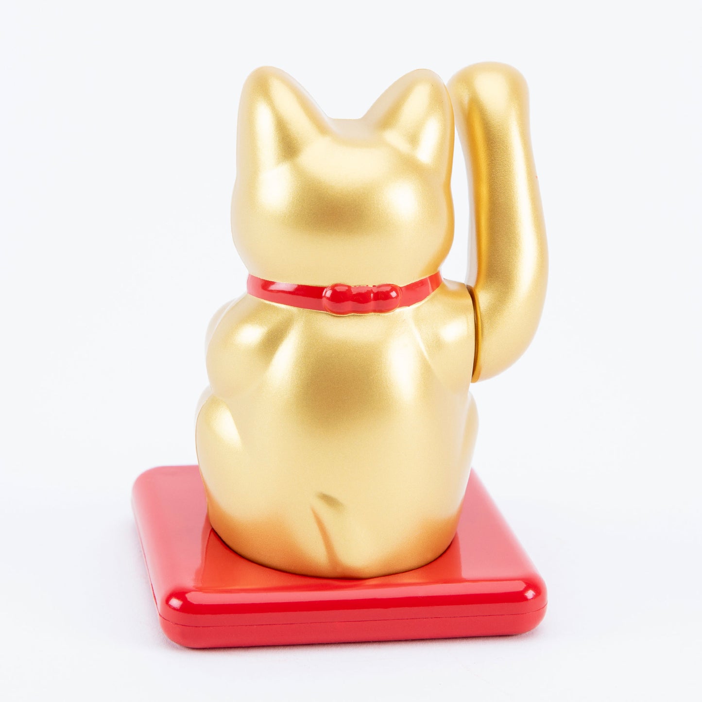 Gold maneki-neko cat on a red base with a white background