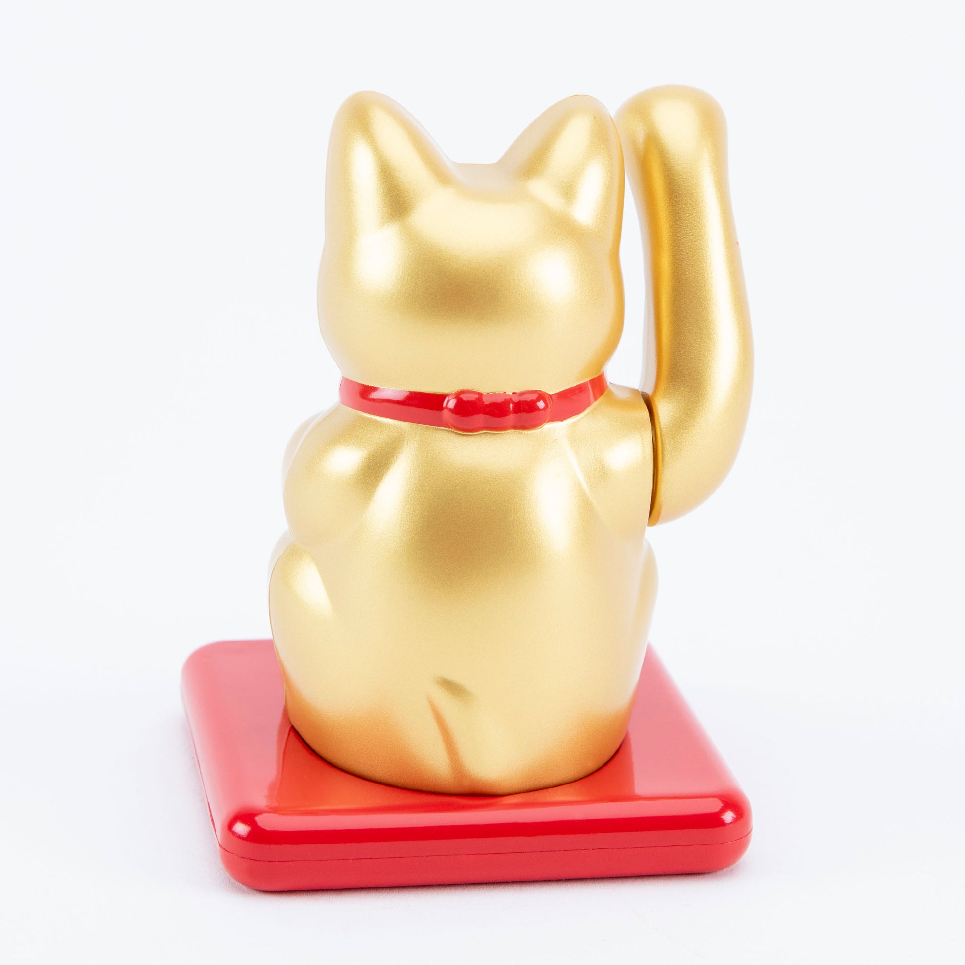 Gold maneki-neko cat on a red base with a white background