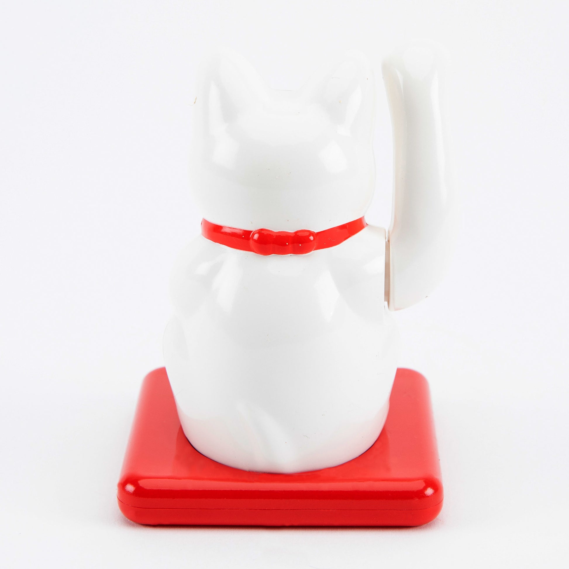 White maneki-neko cat on a red base with a white background