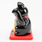 Black maneki-neko cat on a red base with a white background