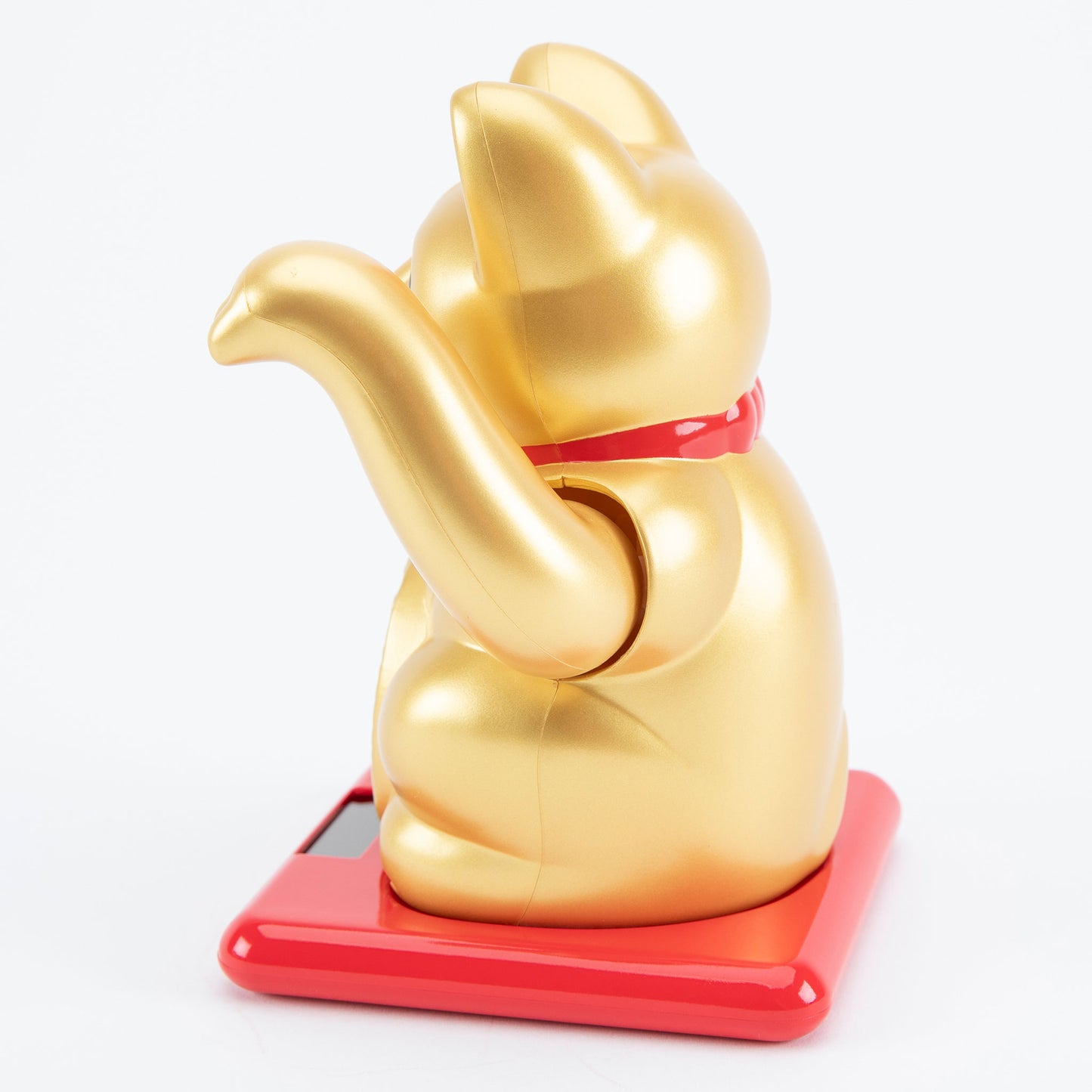 Gold maneki-neko cat on a red base with a white background
