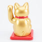 Gold maneki-neko cat on a red base with a white background