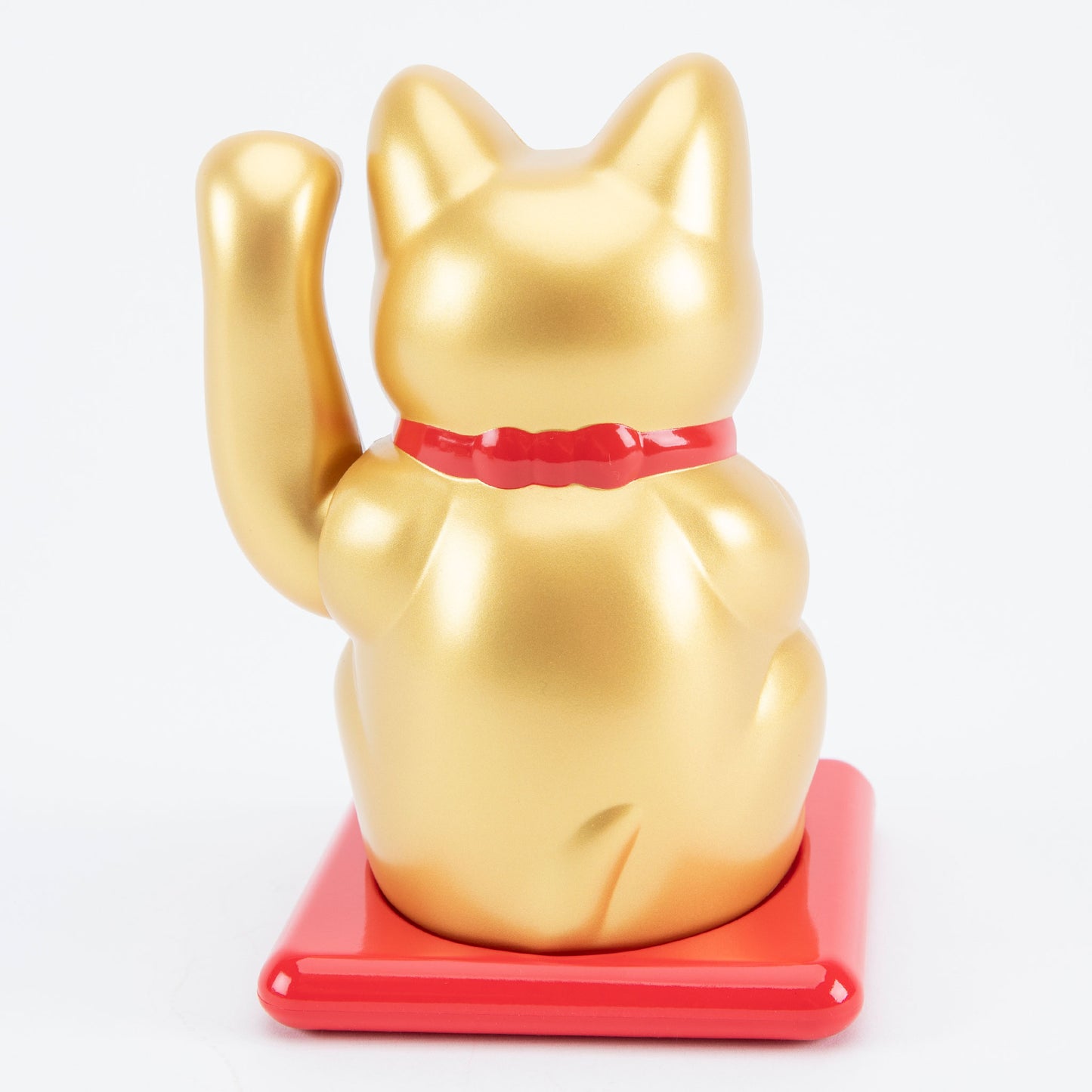 Gold maneki-neko cat on a red base with a white background