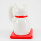 White maneki-neko cat on a red base with a white background