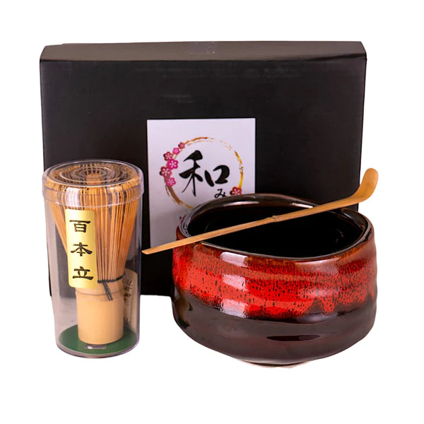 Tea set with red teapot, transparent cup, and wooden spoon on a white background