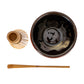 Black ceramic bowl with wooden whisk and scoop on a white background