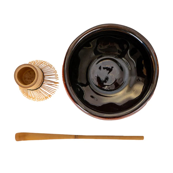 Black ceramic bowl with wooden whisk and scoop on a white background