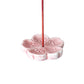 Pink ceramic incense holder with a single red incense stick on a white background
