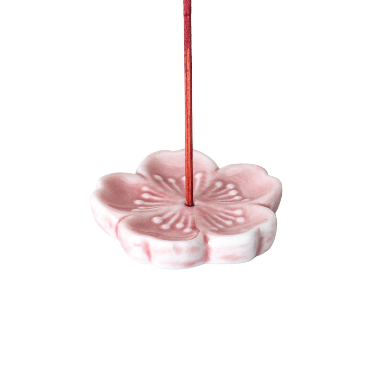 Pink ceramic incense holder with a single red incense stick on a white background