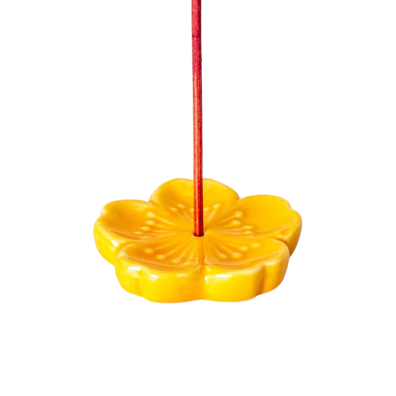 Yellow flower-shaped incense holder on a white background