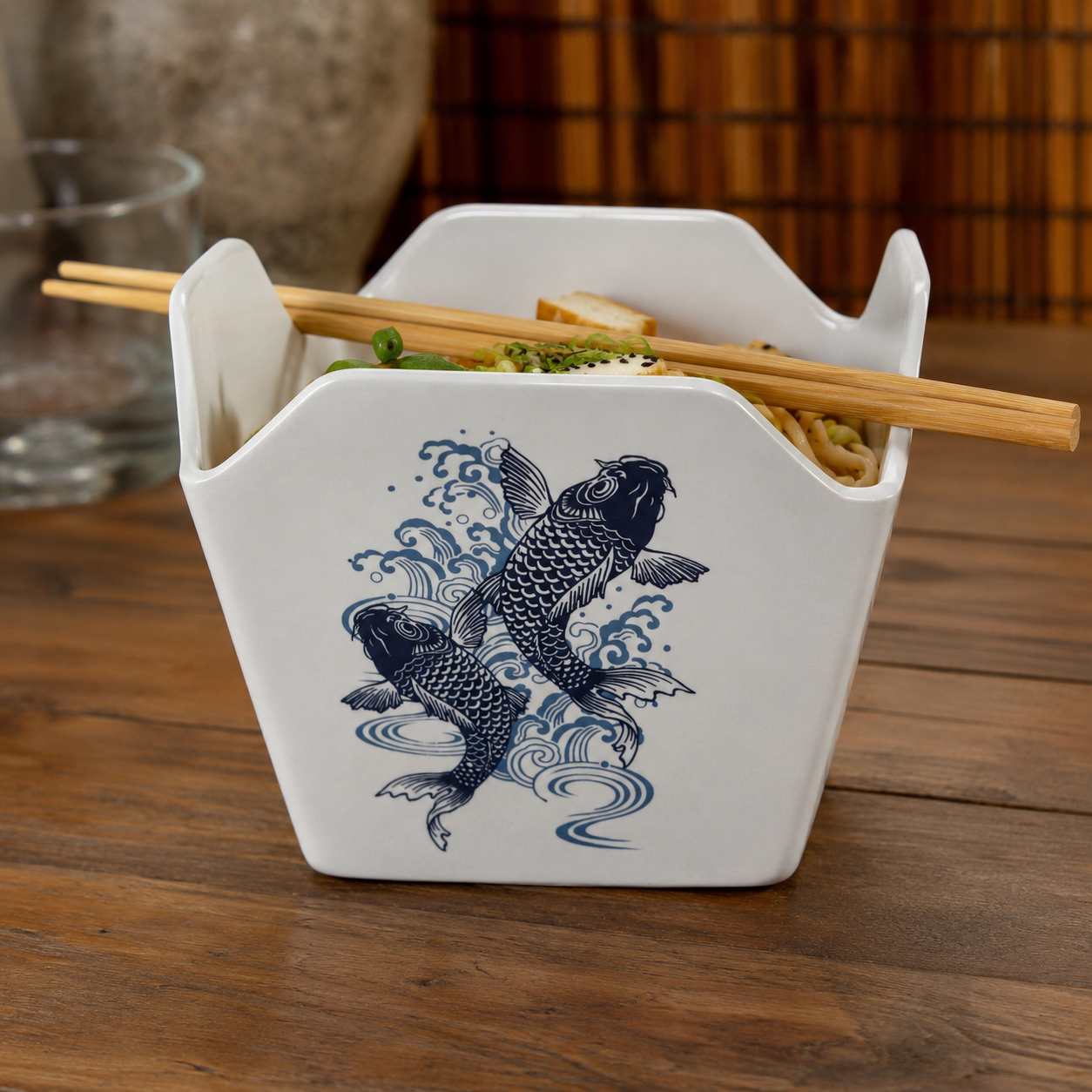 Reusable Takeout Box with koi fish artwork on the front, and filled with ramen noodles.